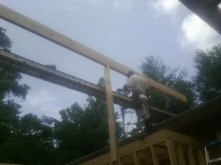 Carpenter setting a ridge beam over a new addition frame — Ice Dam Removal by Roofing Brothers in Orange Springs