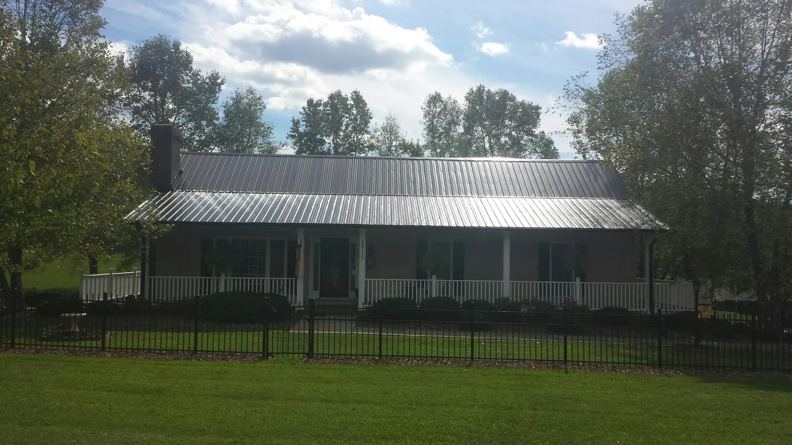 Gray metal roof on a brick ranch with a full width front porch — Gutter Guard Installation work by our crew in Orange Springs