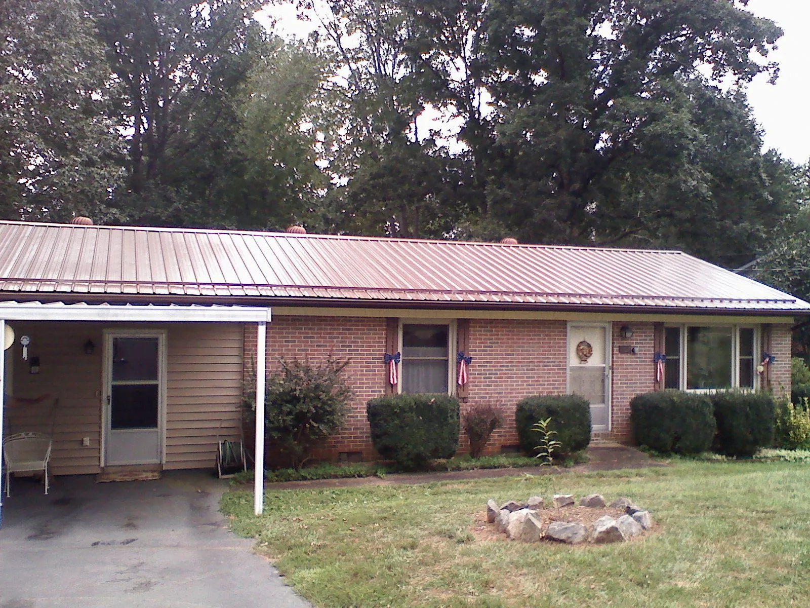 Bronze metal roof and carport on a brick ranch home — Roof Repair work by our crew in Orange Springs