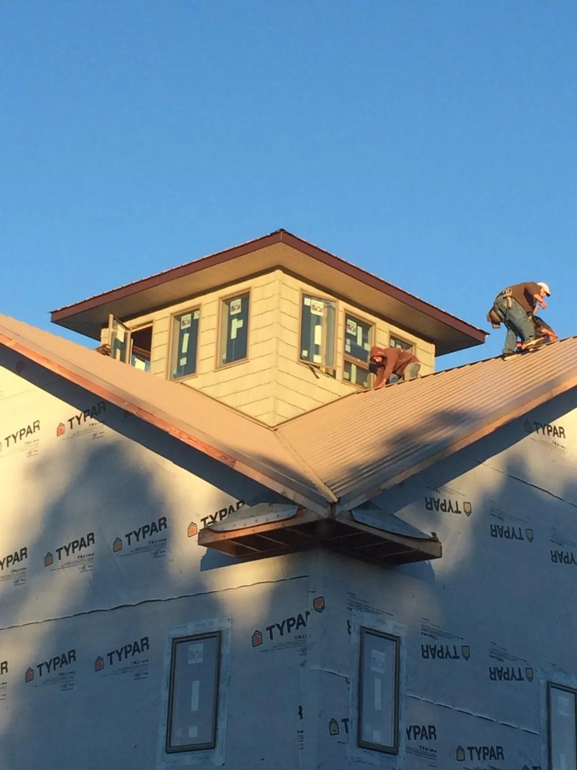 Roofers working around a rooftop cupola on a new metal roof at sunset — Roof Waterproofing in Orange Springs by Roofing Brothers